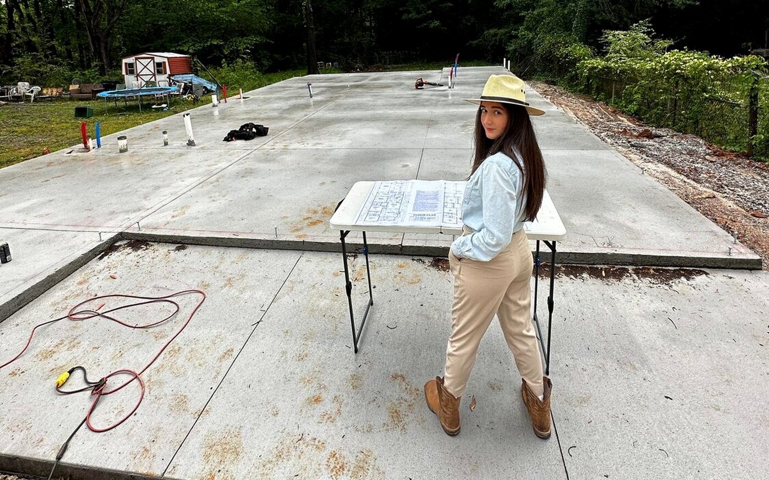 América Ahumada sobre la losa de un terreno en obra, revisando el plano de la casa